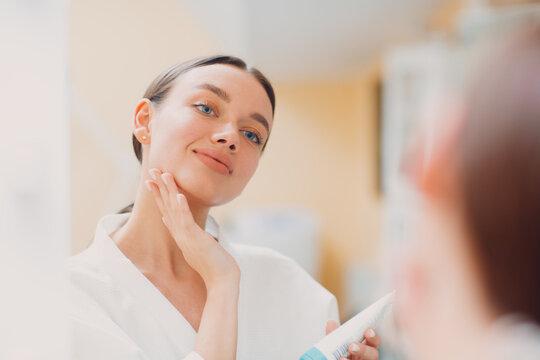 Young woman doing face yoga building facial gymnastics self massage - a woman in a white robe is loo