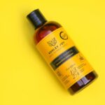 10 Best Seborrheic Dermatitis Shampoos - Top view of Ashley Joy Strength Shampoo with vibrant yellow background.