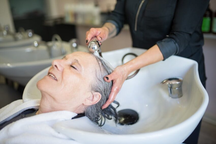 Best 5 Hair Dyes for Seborrheic Dermatitis - Top Choices for 2023 - Elderly woman enjoying a soothing hair wash in a stylish Portuguese salon, capturing a tranquil moment.
