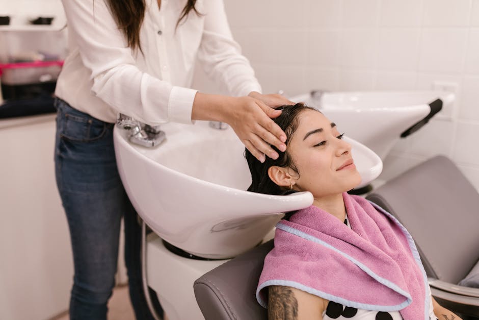 Best Conditioner for Seborrheic Dermatitis 2026: Top Picks for Scalp Relief - A woman enjoys a relaxing hair wash at a modern salon, symbolizing self-care and pampering.