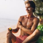 Best Sunscreens for Seborrheic Dermatitis 2026: Top 10 Picks for Sensitive Skin - Adult man applies sunscreen on sunny beach, enjoying summer vacation.