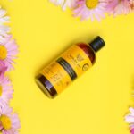 DHS Tar Shampoo: An Effective Solution for Seborrheic Dermatitis - A vibrant yellow shampoo bottle surrounded by fresh daisy flowers on a bright background.