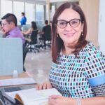 Hypochlorous Acid Spray for Seborrheic Dermatitis: Does It Work? (2026 Guide) - Confident woman in a modern office, surrounded by colleagues, working on a laptop.