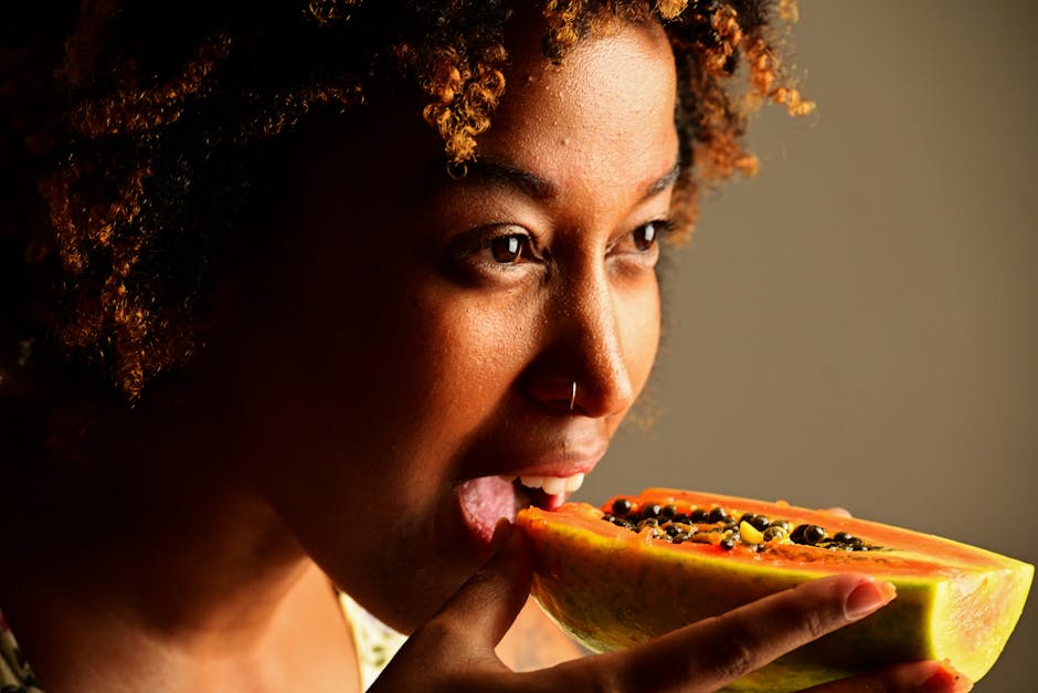 Malassezia-Safe Diet for Seborrheic Dermatitis: Which Foods Actually Matter - A woman savoring a papaya slice, highlighting natural textures and vibrant colors.
