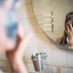 Managing Seborrheic Dermatitis in Aging Individuals: Expert Tips - An elderly woman applying a face mask while looking in the bathroom mirror promoting self-care.