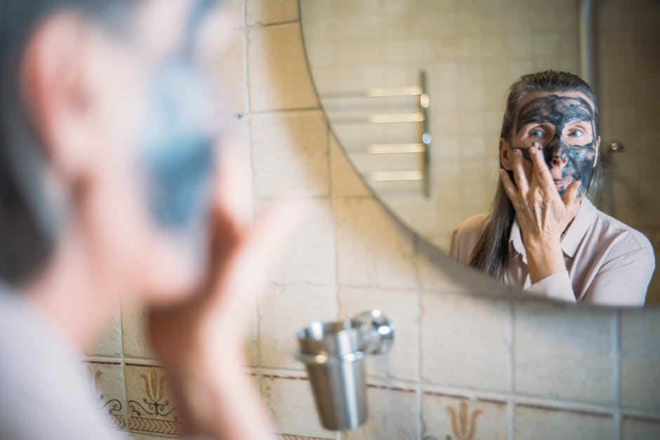Managing Seborrheic Dermatitis in Aging Individuals: Expert Tips - An elderly woman applying a face mask while looking in the bathroom mirror promoting self-care.