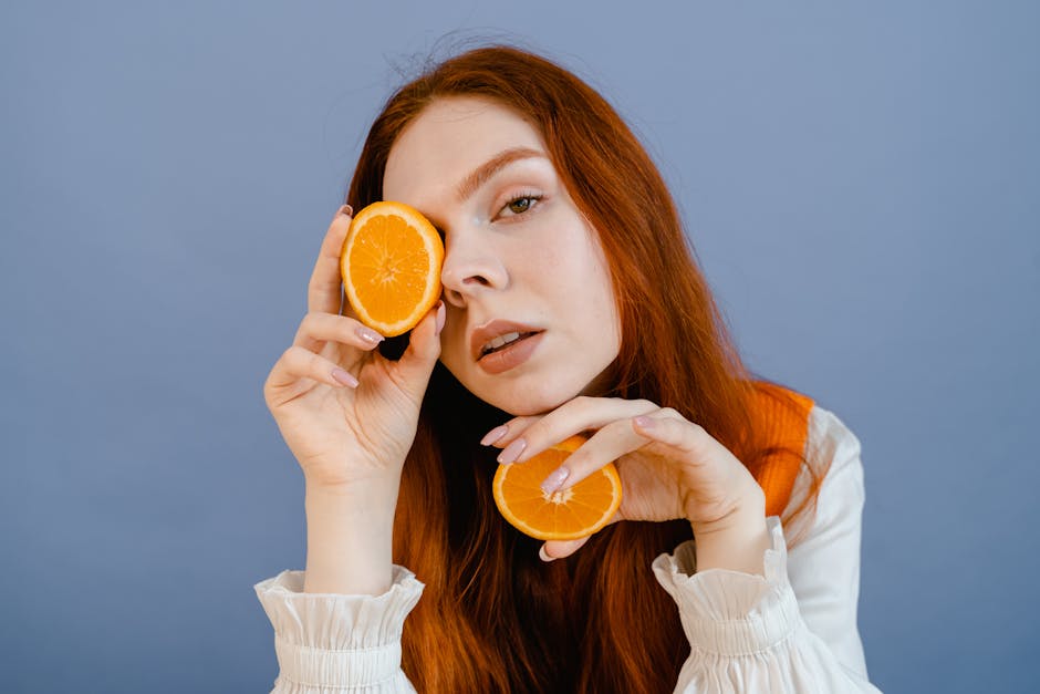 Managing Seborrheic Dermatitis: Unveiling the Diet Link for Relief - Vibrant portrait of a young woman with ginger hair holding orange slices against a blue background.