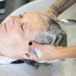 Seborrheic Dermatitis and Curly Hair: Scalp Care Guide (2026) - Elderly woman being pampered with a shampoo at a salon, showcasing relaxation and care.