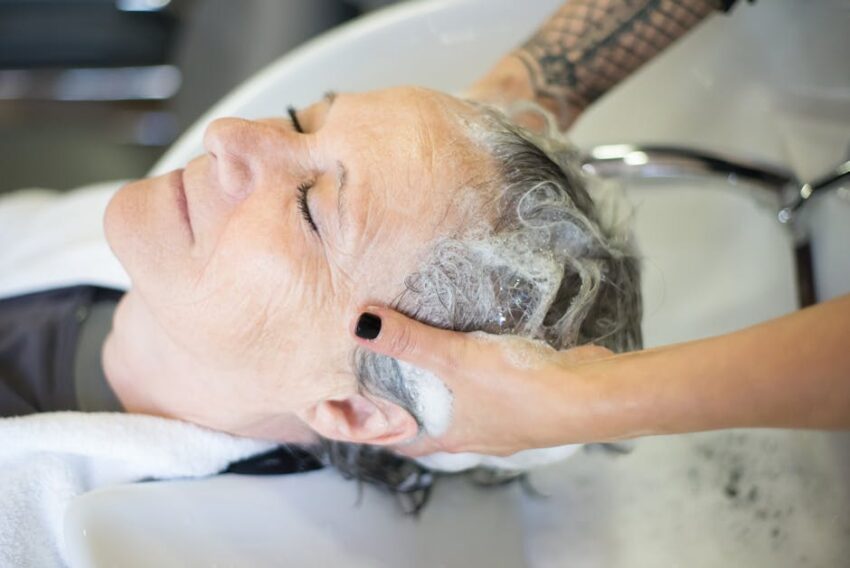 Seborrheic Dermatitis and Curly Hair: Scalp Care Guide (2026) - Elderly woman being pampered with a shampoo at a salon, showcasing relaxation and care.