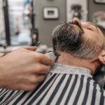 Seborrheic Dermatitis and Face Oils: Which Oils are Safe and Which Trigger Flares? (2026) - Close-up of a professional barber trimming a man's beard in a stylish barbershop.