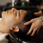 Seborrheic Dermatitis and Scalp Buildup: Your Complete Guide to a Healthy Scalp - Man with closed eyes enjoying a relaxing hair wash at salon sink by a professional stylist.