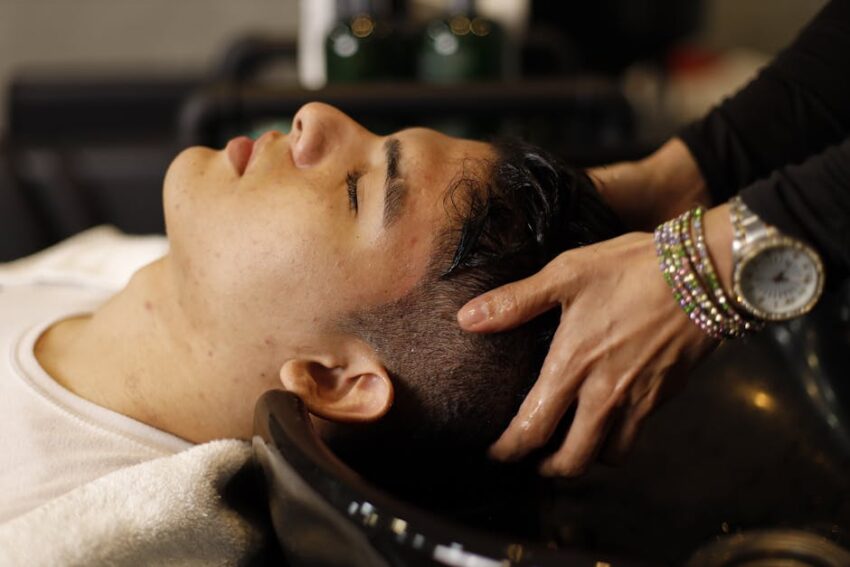 Seborrheic Dermatitis and Scalp Buildup: Your Complete Guide to a Healthy Scalp - Man with closed eyes enjoying a relaxing hair wash at salon sink by a professional stylist.