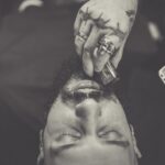 Seborrheic Dermatitis Beard Care: How to Treat Beard Dandruff Without Ruining Your Facial Hair (2026) - Close-up of a barber trimming a man's beard with closed eyes, in grayscale.