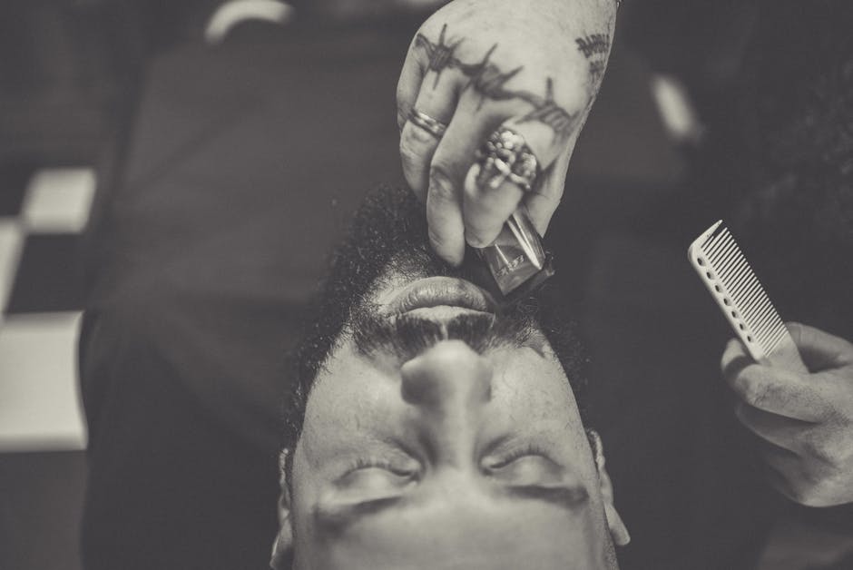 Seborrheic Dermatitis Beard Care: How to Treat Beard Dandruff Without Ruining Your Facial Hair (2026) 6 Seborrheic Dermatitis Beard Care: How to Treat Beard Dandruff Without Ruining Your Facial Hair (2026) - Close-up of a barber trimming a man's beard with closed eyes, in grayscale.