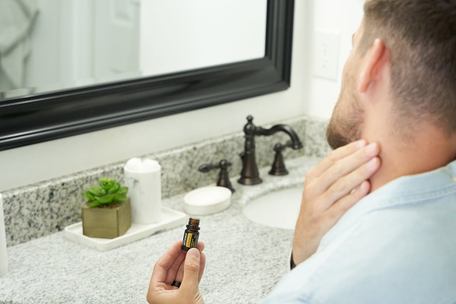 Seborrheic Dermatitis Beard Treatment Guide 2026: How to Manage Flaking, Itching & Redness Under Facial Hair - Adult man in bathroom holding an essential oil bottle near mirror, focusing on grooming and self-care.