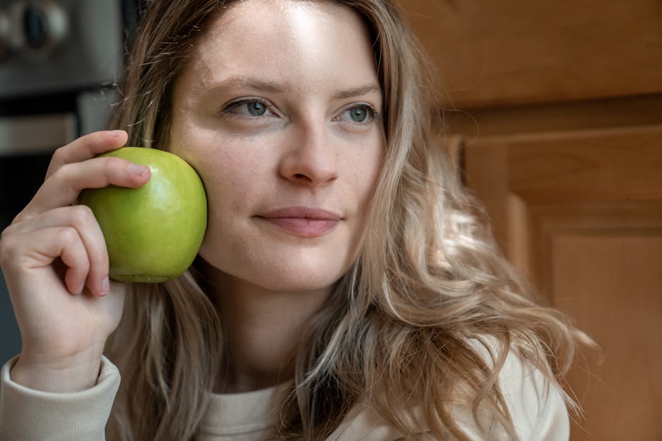Seborrheic Dermatitis Diet Guide: Foods That May Help and What to Avoid (2026) - Close-up portrait of a woman indoors holding a green apple, showcasing natural beauty and health.