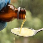 Seborrheic Dermatitis or Dry Scalp? How to Tell the Difference Before You Buy Another Shampoo - A gloved hand pours liquid medication from a brown bottle into a spoon.