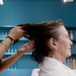 Seborrheic Dermatitis or Dry Scalp? How to Tell the Difference (2026) - An elderly woman enjoying a stylish hair treatment by a professional hairstylist in a salon.