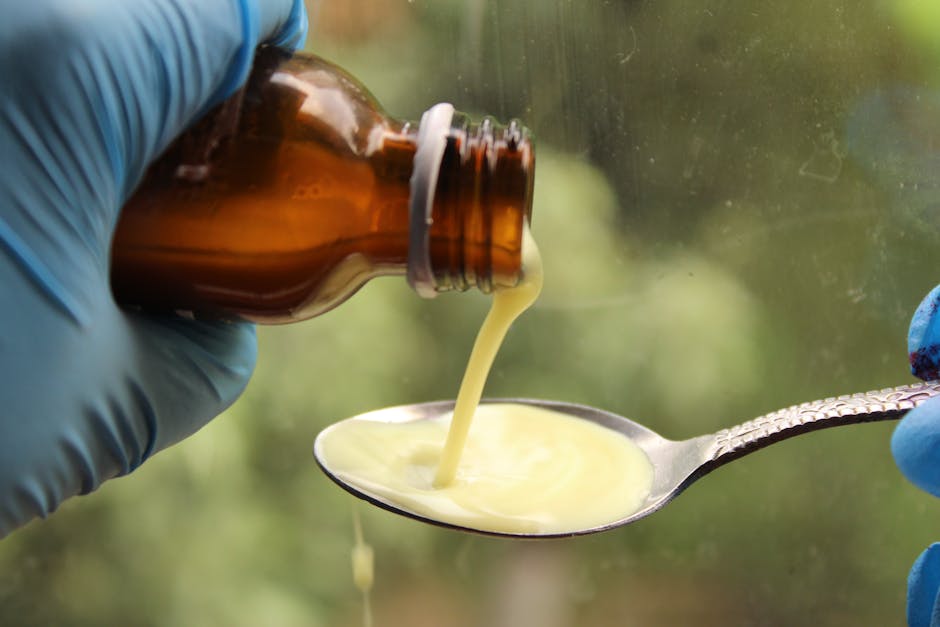 Seborrheic Dermatitis or Dry Scalp? How to Tell the Difference Before You Buy Another Shampoo - A gloved hand pours liquid medication from a brown bottle into a spoon.