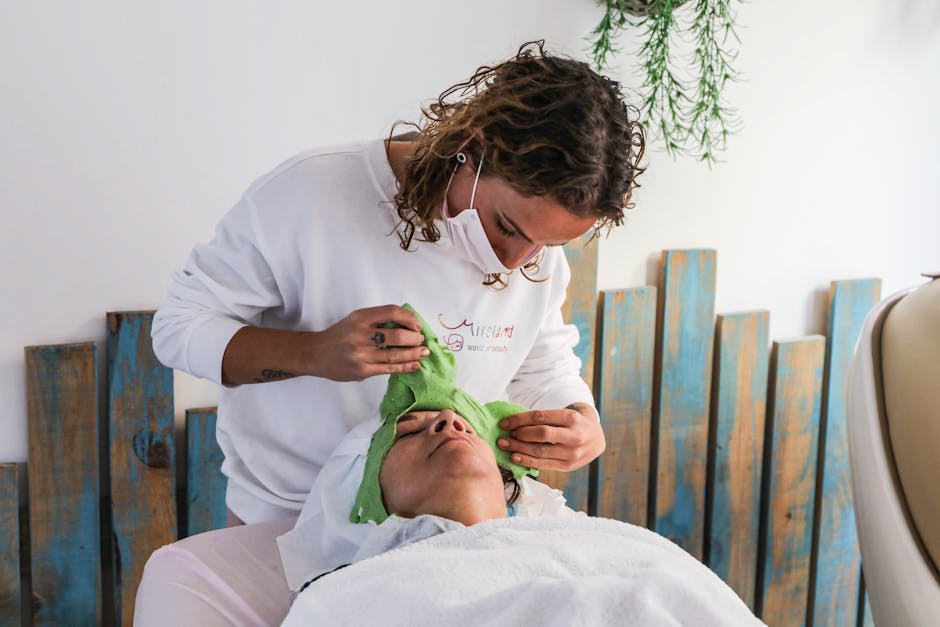 Seborrheic Dermatitis or Dry Scalp? How to Tell the Difference (2026) - A spa therapist applies a green facial mask during a relaxing spa treatment.