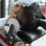 Seborrheic Dermatitis vs Dry Scalp on the Face: How to Tell the Difference - Close-up of a man receiving a haircut with an electric shaver, assisted by a hairdresser.
