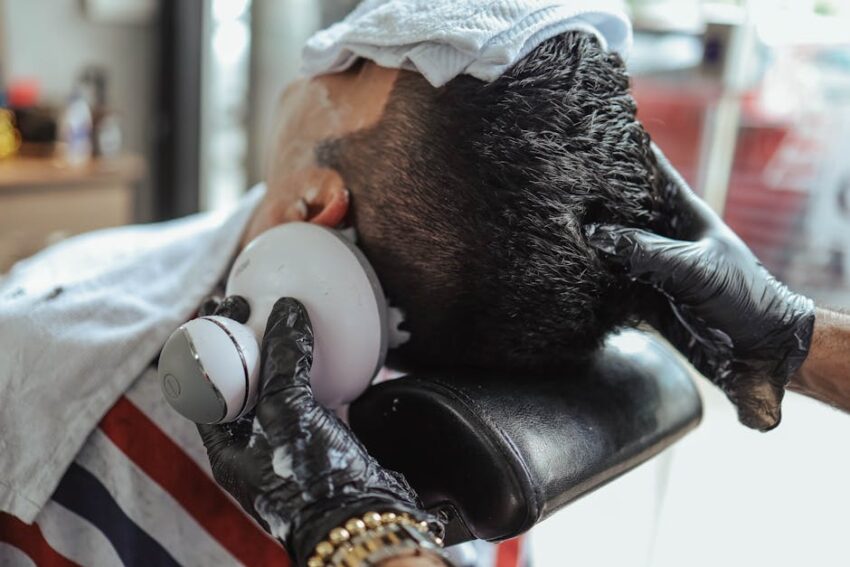 Seborrheic Dermatitis vs Dry Scalp on the Face: How to Tell the Difference - Close-up of a man receiving a haircut with an electric shaver, assisted by a hairdresser.