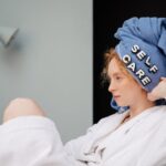 Self-Care Tips - Relaxed woman in a bathrobe with a towel headwrap featuring 'self care' letters enjoying a moment at home.
