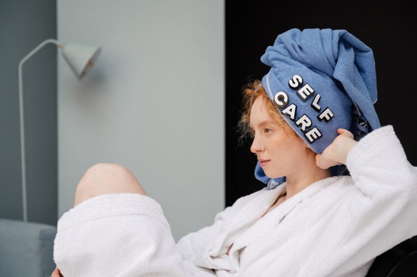 Self-Care Tips - Relaxed woman in a bathrobe with a towel headwrap featuring 'self care' letters enjoying a moment at home.