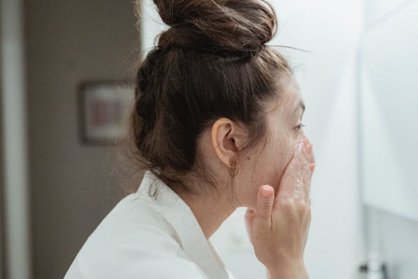 The Ultimate Guide to Treating Seborrheic Dermatitis: Find Your Perfect Face Wash - A young woman in a bathrobe follows her skincare routine, washing her face in a bathroom.