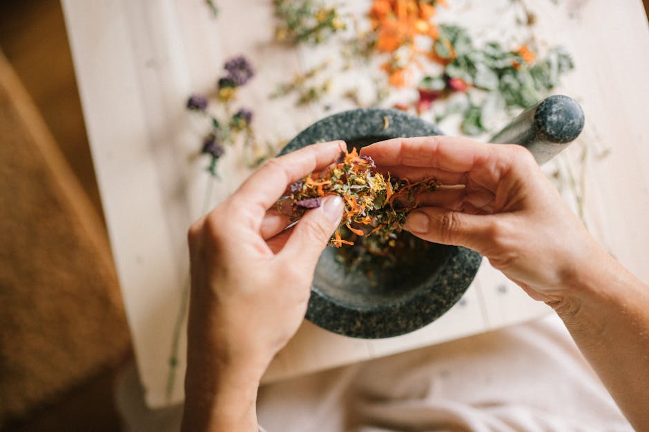 Unveiling Effective Cultural Remedies for Seborrheic Dermatitis - Close-up of hands preparing herbal ingredients in a mortar and pestle, top view.