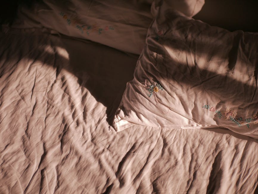 Upgrade Your Sleep Routine: The Best Cotton Pillowcases for Seborrheic Dermatitis - Embroidered pink pillowcase and bedsheet in warm sunlight creating a cozy atmosphere.
