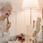 Why Seborrheic Dermatitis Keeps Coming Back: Managing the Relapse Cycle (2026) - Elderly woman using makeup brush at dresser by candlelight.