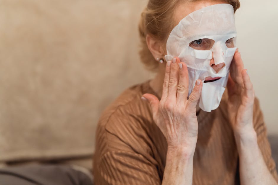 Why Seborrheic Dermatitis Keeps Coming Back: Managing the Relapse Cycle (2026) - A senior woman applies a hydrating sheet mask for skincare indoors, focusing on facial rejuvenation.