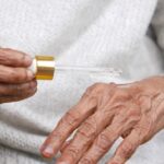 Winning Title: Can Helping Your Immune System Aid In Managing Seborrheic Dermatitis? - Close-up of elderly hands applying serum with dropper, focusing on skincare and aging.