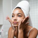 Best Seborrheic Dermatitis Face Washes 2026 | SebDermatology - Young woman practicing skincare routine with a towel wrap indoors.