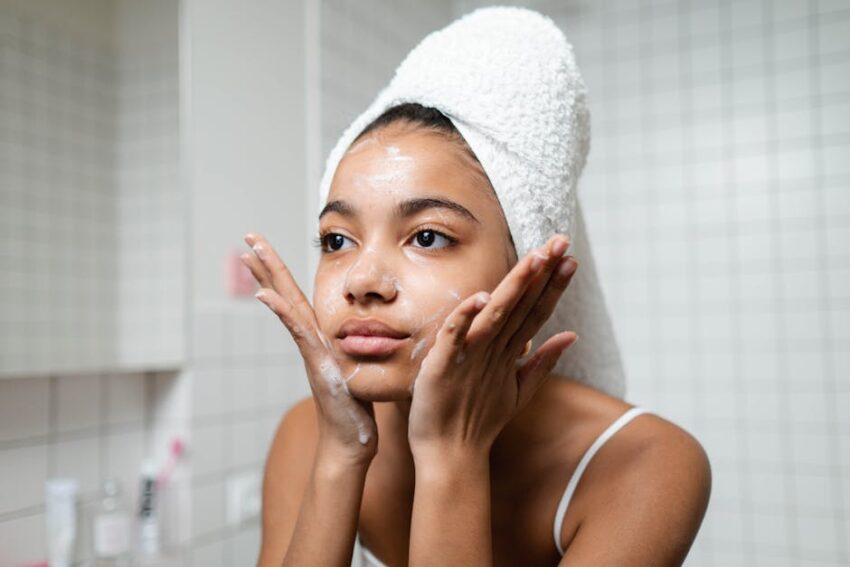 Best Seborrheic Dermatitis Face Washes 2026 | SebDermatology - Young woman practicing skincare routine with a towel wrap indoors.