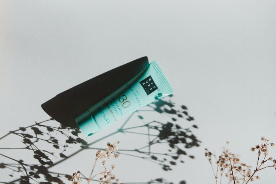 Dermoscribe Seborrheic Dermatitis Cream Review: Sulfur + Salicylic Acid Formula Analyzed (2026) - Simple composition of a sun protection cream tube casting botanical shadows, highlighting beauty and skincare.
