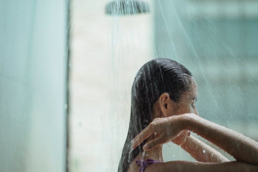 dermstore-premium-seb-derm-routine - Side view of lady with closed eyes standing in shower and enjoying water