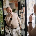 mct-oil-seborrheic-dermatitis-guide-2026 - Middle-aged man applying beard care, examining reflection indoors, embracing modern grooming.