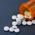 Non-Steroidal Topicals for Seborrheic Dermatitis: What 2026 Evidence Shows - Close-up of white pills scattered from an orange prescription bottle on a gray surface.