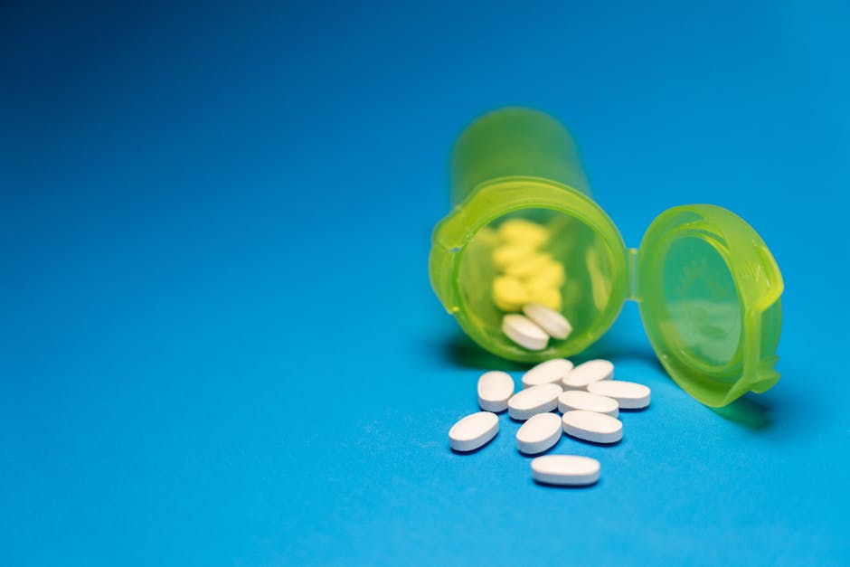 Non-Steroidal Topicals for Seborrheic Dermatitis: What 2026 Evidence Shows - Image of a green pill bottle with white tablets scattered on a blue background, symbolizing healthcare and medication.