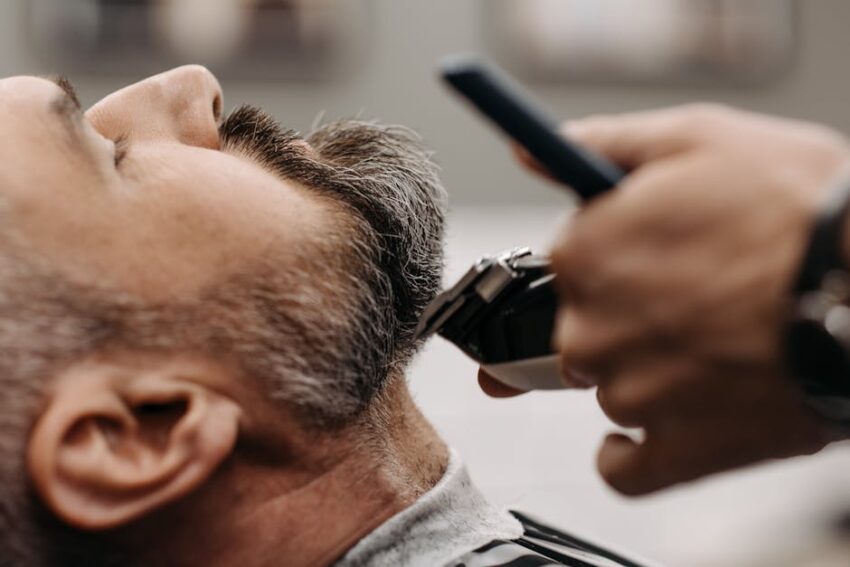 safe-face-oils-seborrheic-dermatitis-2026 - Close-up of a barber using clippers to groom a client's beard in a barbershop.
