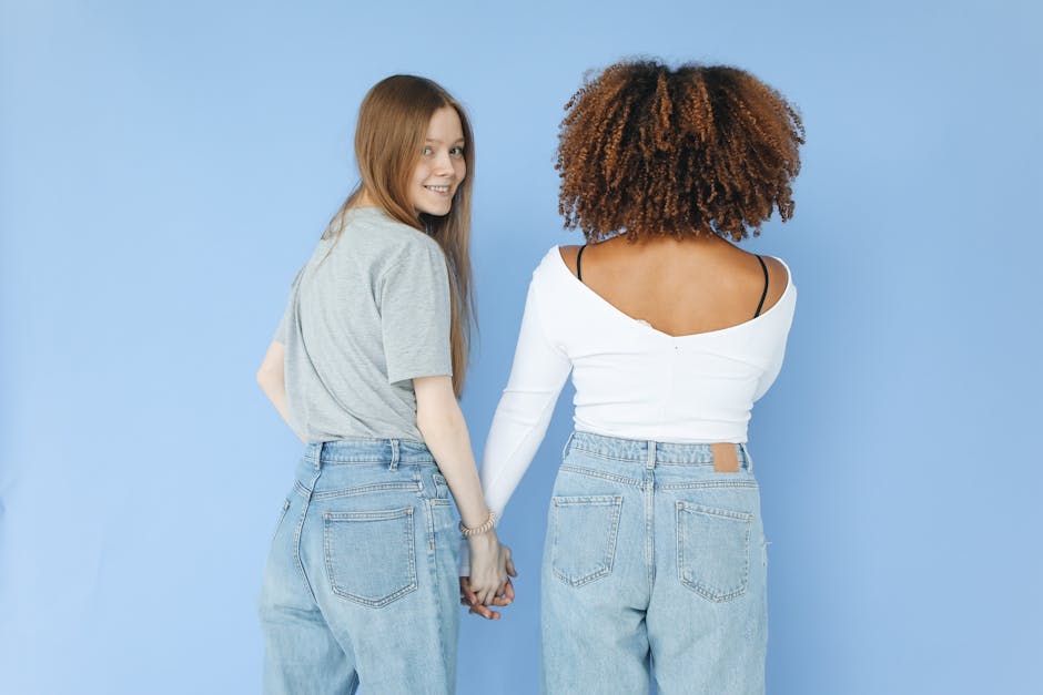 seb-derm-myths-debunked-2026 - Two women standing and holding hands against a blue background, showcasing friendship.