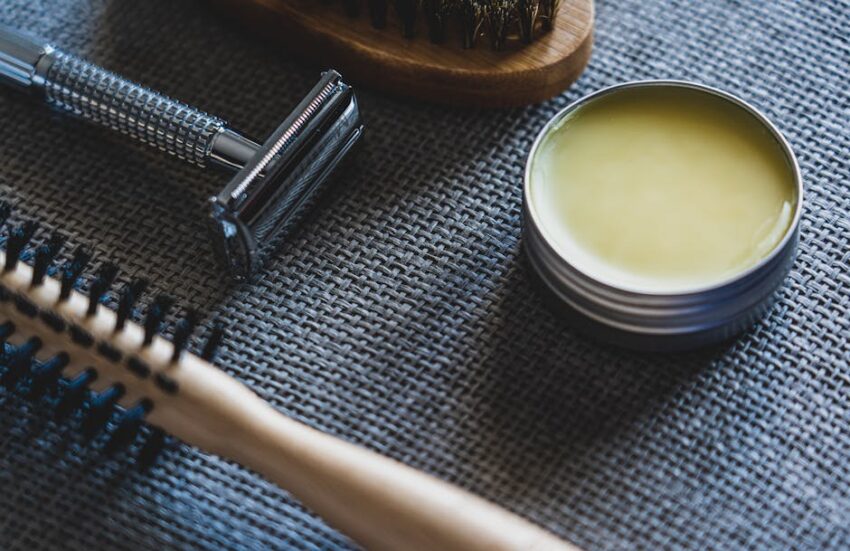 seborrheic-dermatitis-beard-treatment-guide-2026 - A flat lay of grooming tools including a razor, brush, and pomade on a textured surface.