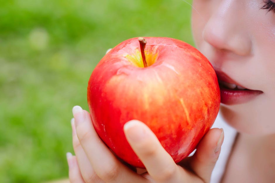 seborrheic-dermatitis-diet-foods-elimination-guide-2026 - Close-up of a woman holding a bright red apple outdoors, highlighting healthy living and freshness.