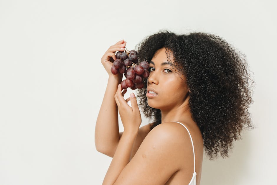 seborrheic-dermatitis-diet-guide-2026 - A woman holding grapes against a white background, captured in a studio setting.