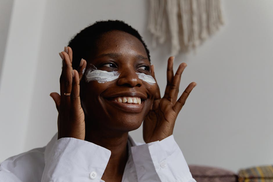 seborrheic-dermatitis-face-treatment-guide-2026 - Black woman applying face cream indoors, smiling joyfully in natural lighting.