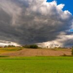 summer-emergency-seb-derm-flare-care-quick-relief-strategies-2026 - A picturesque rural landscape with dramatic storm clouds gathering over green fields and farmland.