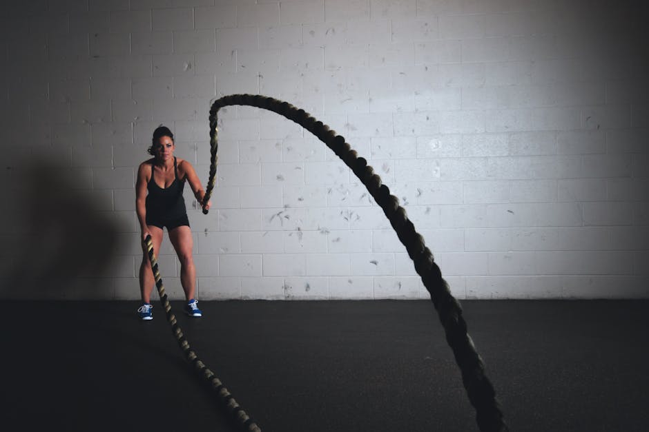sweat-wicking-products-seborrheic-dermatitis-summer-2026 - A focused woman performs a dynamic battle rope exercise in a gym setting, demonstrating strength and fitness.