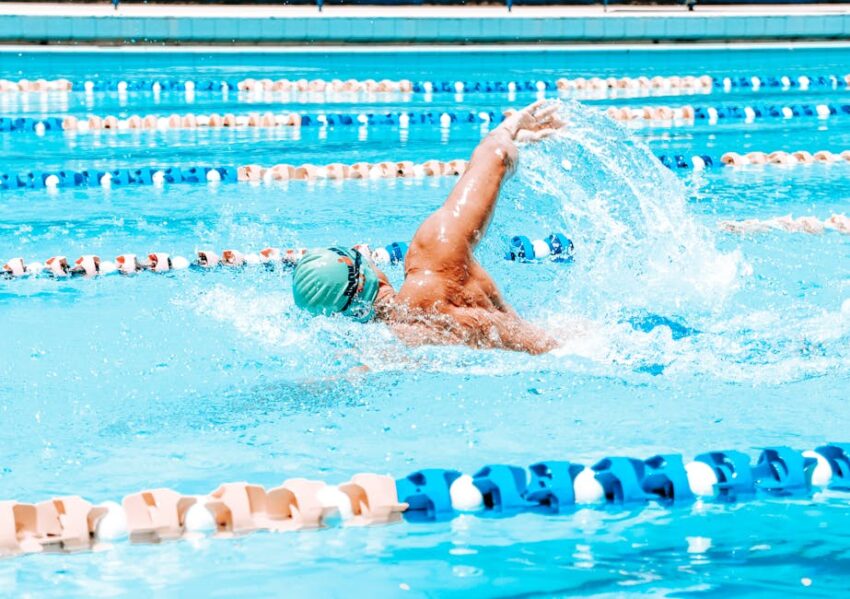Swimming & Seb Derm: 2026 Safety Guide | SebDermatology - Energetic swimmer performing a stroke in a bright outdoor pool under sunlight in Maceió, Brazil.